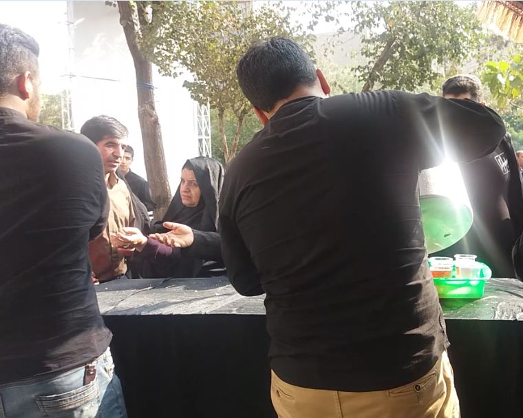  خادمان حسینی در حال توزیع شربت در ایستگاه صلواتی هیئت و خدمت به زائران حسینی از راه دور هستند